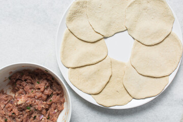 Overhead view of rolled out bao dough, top view of baozi dough rolled out on a white countertop