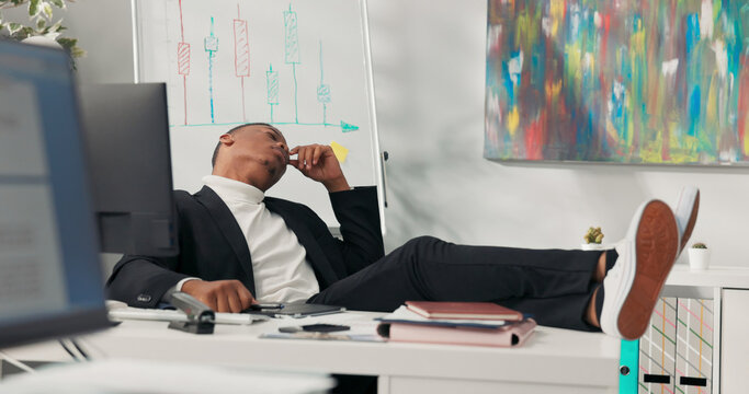 Dark-skinned handsome company boss sits comfortably in chair with feet on desk rests with eyes closed rises quickly gets brilliant idea clicks keyboard searches for information, smiling, cheerful