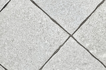 Close-up of light gray square tiles with a rough texture, arranged in a diagonal pattern. Visible...