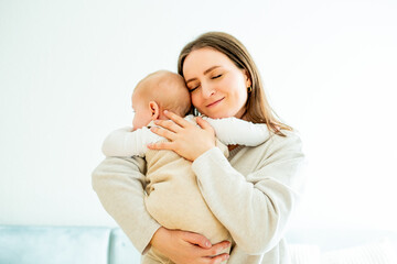 Happy mother holding her little son 9 months in her arms at home.