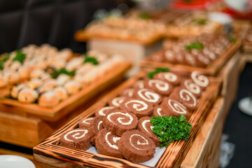 A table filled with dishes like chocolate rolls and sushi, neatly presented and garnished with...