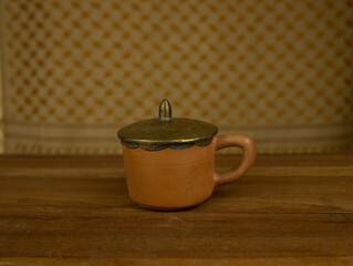 Terracotta teapot with brass accents wooden surface no people warm lighting highlight traditional craftsmanship