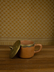 Terracotta teapot with brass accents wooden surface no people warm lighting highlight traditional craftsmanship