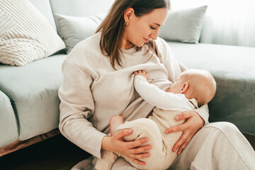 Happy mother breastfeeding her little baby in her arms at home
