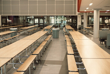 Trash cans setup between row of empty rectangle mobile cafeteria table with bench seats for easy sit close, spread out at middle school in Dallas, Texas, laminate top resists scratches and stains