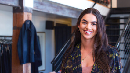 Portrait Of Smiling Female Owner Of Fashion Store Standing In Front Of Clothing Display