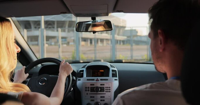 Car instructor teaches a young woman how to pass driving license examination. Driver courses, exam and people concept.
