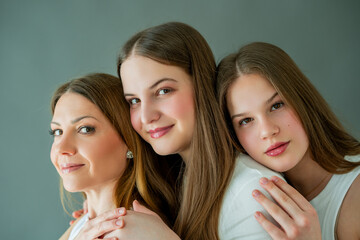 Two teenage daughters hugging their young mother at home.