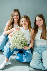 Two teenage daughters hugging their young mother at home.