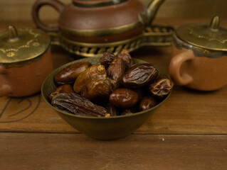 Dates in brass bowl wooden surface no people warm lighting traditional Middle Eastern setting