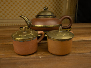 Terracotta teapot with brass accents wooden surface no people warm lighting highlight traditional...