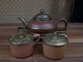 Terracotta teapot with brass accents wooden surface no people warm lighting highlight traditional...