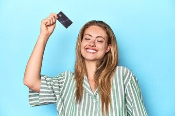 Young blonde woman holding a credit card in a studio