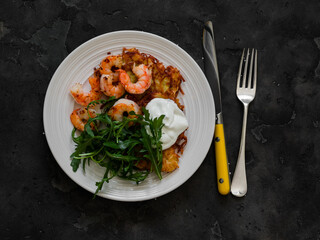 Potato latkes, shrimp, arugula - delicious breakfast, brunch, snack, tapas on a dark background, top view