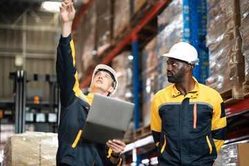African American and White employee holding laptop, worker in yellow collar having conversation...