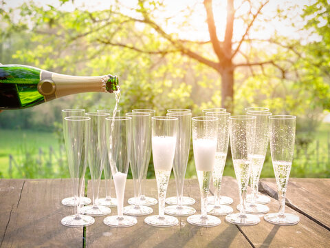 Hand pouring wine into flute glasses of champagne
