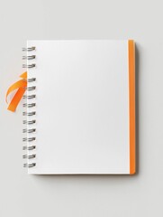 Photograph of a blank white notebook with an orange ribbon tied around the top. the notebook has a spiral binding on the left side and an orange strip on the right side.