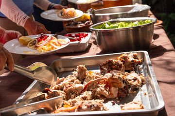 Roasted pork placed on a tray surrounded by a buffet of various dishes and fresh salads. 