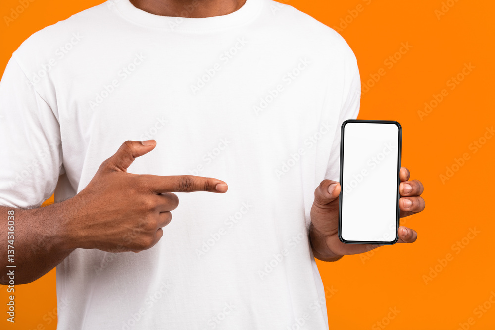Poster black man showing smartphone with blank screen recommending mobile app on yellow background. mockup,