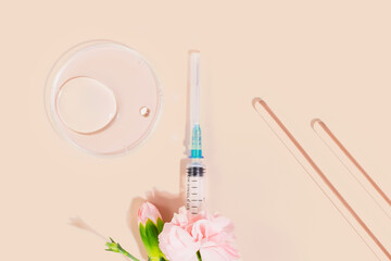 Syringe with pink flowers, lab tools, and petri dish on nude background. Concept of beauty...