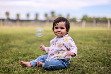 Little girl playing with bubbles in garden, nice day and funny
