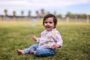 Little girl playing with bubbles in garden, nice day and funny