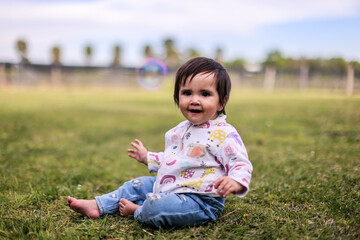Little girl playing with bubbles in garden, nice day and funny