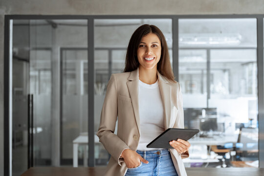 Female portrait latin ceo leader business woman in office, holding digital device, looking at camera. Middle age manager specialist businesswoman using tablet pc at work for financial data analyzing