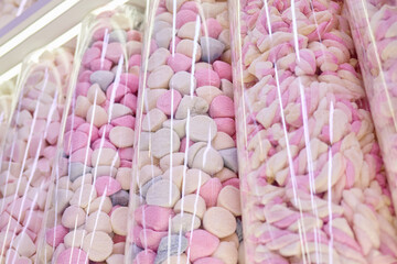 Shelves filled with pastel-colored marshmallows create a vibrant and inviting atmosphere in the candy shop. Bright pinks and soft whites entice visitors who love sweets