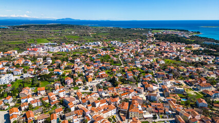Aerial view of Medulin and the Church of St. Agnes, showcasing the charming coastline of Croatia. The picturesque scenery includes crystal-clear waters, historic architecture, and a beautiful Adriatic