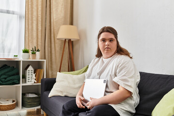 Strong young woman with Down syndrome enjoying a cozy moment at home while holding a tablet