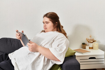 Young woman with Down syndrome enjoying a cozy moment at home while using her tablet