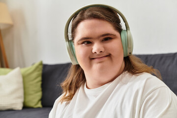 Young woman with Down syndrome enjoys cozy time at home while listening to music and smiling