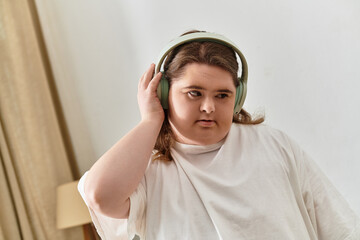 Young woman with Down syndrome enjoys music in a cozy home setting while feeling confident