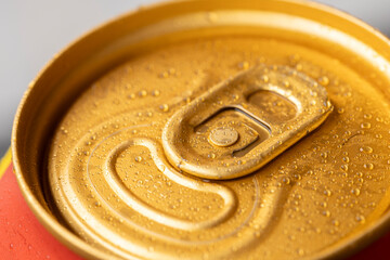 Close-up image of a beer can with multiple drops of water, the can is gold in color