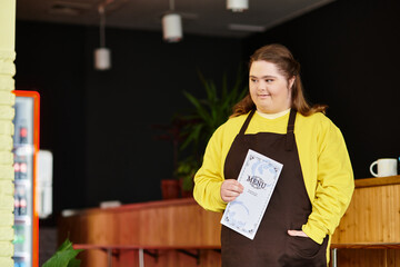 Strong and confident young woman with Down syndrome showcases menu in cozy cafe atmosphere
