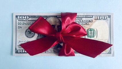 100-dollar bills tied with a red ribbon, cash gift concept on blue background	