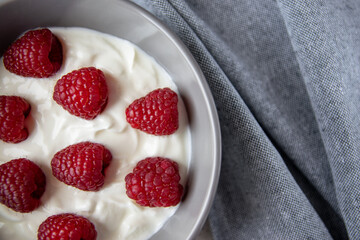 Gray bowl and natural yogurt with berries on the stone marble table.