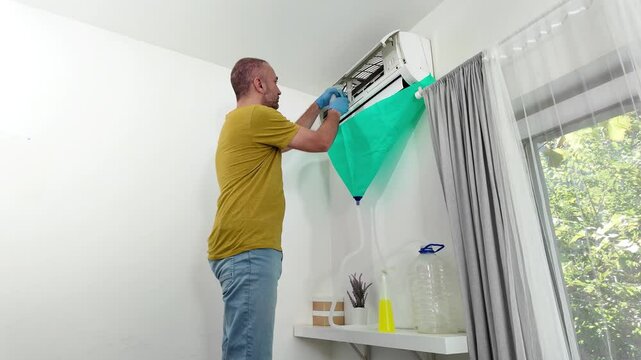 Man cleaning and maintaining air condition unit at home.	
