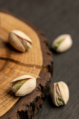 fried unpeeled pistachio nuts in a wooden bowl with cracked shells