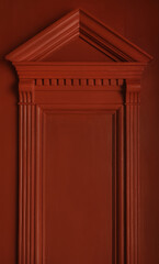 Fragment of a door with carved cornice decoration with a triangular pediment and massive brackets. The rich color emphasizes the architectural details of the historic door © pavlobaliukh