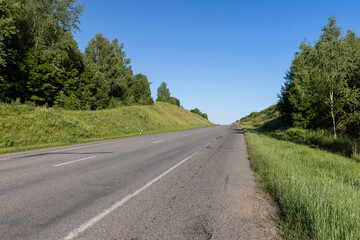 an empty straight paved road against a blue sky background