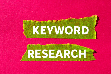 Keyword research message written on ripped torn green paper tape on pink background. Conceptual...