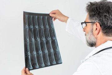 Confident mature neurologist carefully examines a patient's MRI spine scan, analyzing detailed...