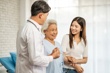 Obraz premium Senior elderly woman delighted after receiving treatment at clinic. Physician doctor and young lady standing beside old patient and smile in hospital room.