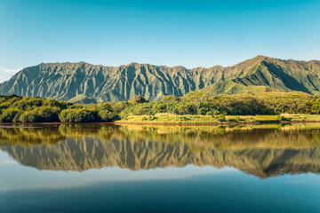 Ko'olau volcanic mountain range reflecting in a calm surface of a lake during sunny day, Oahu...