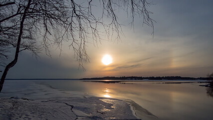 A partial halo effect around the sun over a frozen lake in Finnish nature in early spring