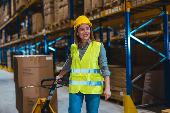 Smiling Warehouse Worker in Safety Gear Operating a Manual Pallet Jack