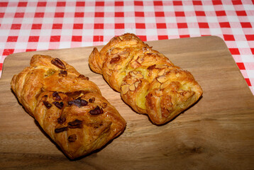 Deliciously flaky pastries filled with nuts and fruits rest on a wooden board. The red and white checkered tablecloth adds a charming touch to the cafe ambiance