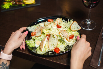 Caesar salad with grilled chicken, croutons, and cherry tomatoes on a black plate